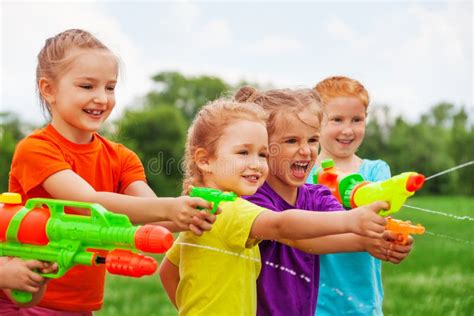 Kids Play With Water Guns On A Meadow Stock Photo Image Of Happy