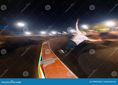Motion In Blur Young Skater Is Rolling Down The Ramp At Night In A