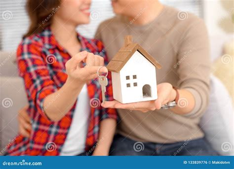 Happy Couple Holding Keys To New Home and House Miniature - Real Stock