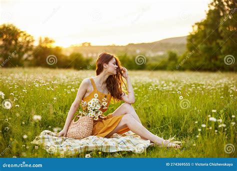 A Beautiful Woman With Long Red Hair In An Orange Dress Sits In A