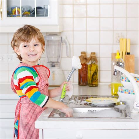 Happy Little Blond Kid Boy Washing Dishes In Domestic Kitchen Stock