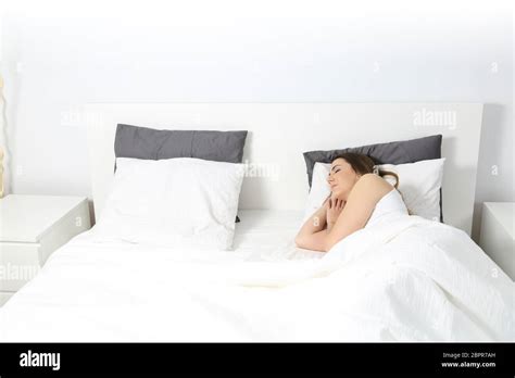Wide Angle View Of A Woman Sleeping In A Bed At Home With An Isolated White Wall In The