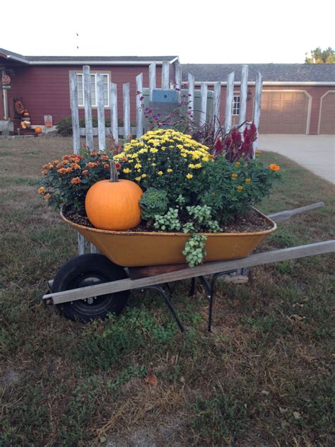 A Wheelbarrow Filled With Flowers And Pumpkins