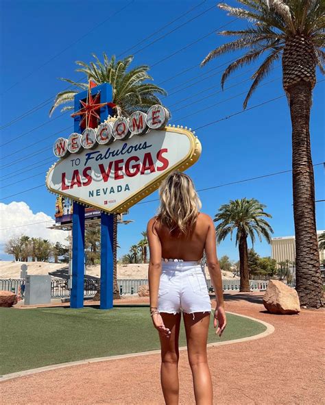 a woman standing in front of the welcome to fabulous las vegas sign with palm trees