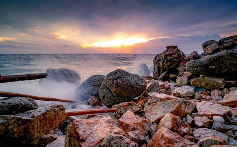 Ocean Water Splash On Rock Beach With Beautiful Sunset Sky And Clouds