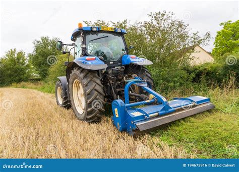 Farmer In A Tractor Mowing A Grass Verge On The Edge Of A Field Uk