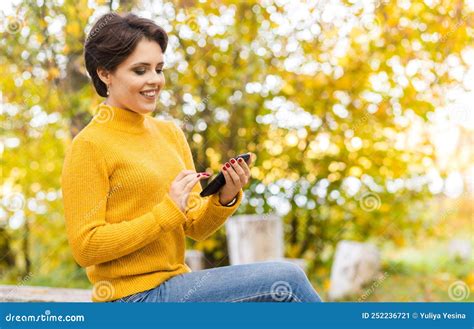 Schöne Junge Brunette Mädchen Posiert Im Herbstpark Mit Einem Handy In Den Händen Stockbild