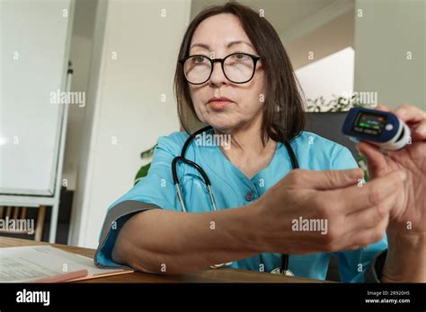 Doctor wearing eyeglasses showing pulse oximeter at medical practice