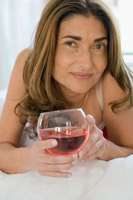 Close Up Of A Mature Woman Lying On The Bed And Holding A Glass Of Wine