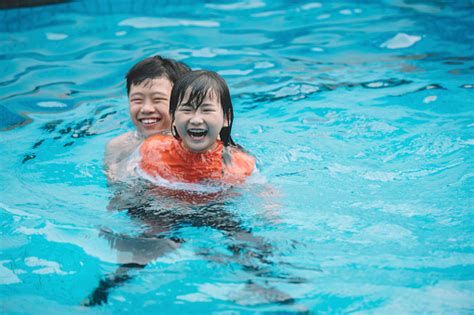 An Asian Chinese Sibling Playing And Having Fun In The Swimming Pool