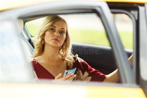 Photo Of Happy Blonde Sitting In Back Seat Of Yellow Taxi With Open