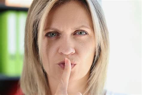 Woman With Serious Face Holds Her Finger On Her Lips And Asks For