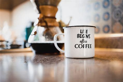 White And Black Life Begins After Coffee Printed Enamel Cup Beside Black Liquid Filled Glass