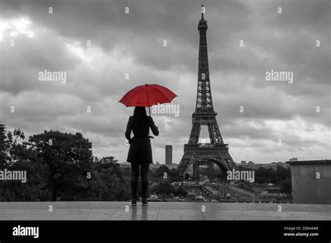 The Lady With A Red Umbrella Is Standing In Front Of The Eiffel Tower