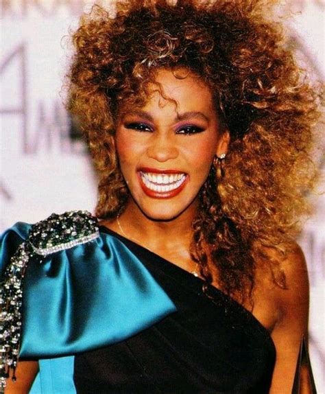 An Image Of A Woman With Curly Hair Smiling At The Camera While Wearing