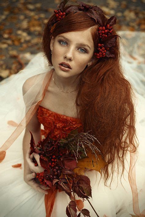 A Woman With Long Red Hair Wearing A White Dress And Holding A Bunch Of Berries