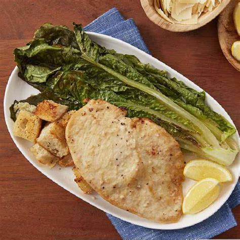 A rectangular white china tray holding three thin lemon cutlets garnished with lemon slices and chopped parsley. PERDUE® FRESH CUTS™ Thin Sliced Boneless Skinless Chicken ...