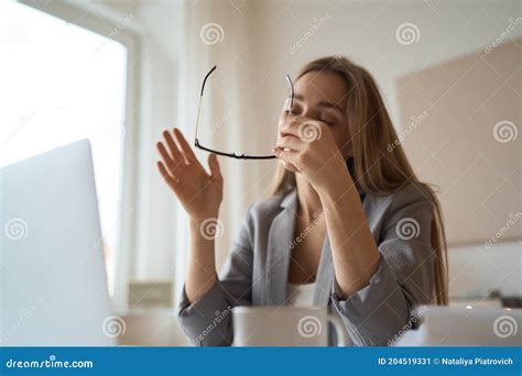 Tired Woman Sitting At Desk With Laptop Holding Head Resting On Hand