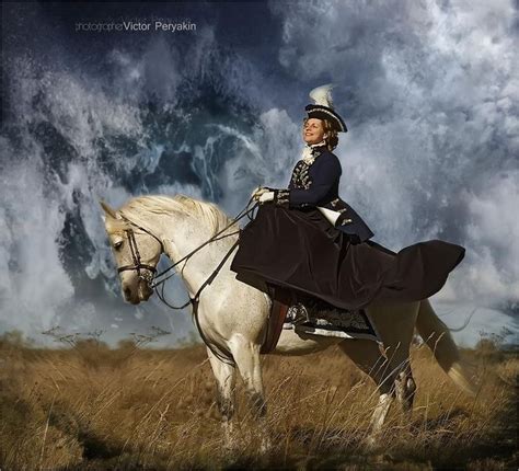 A Woman Riding On The Back Of A White Horse In A Field Under A Cloudy Sky