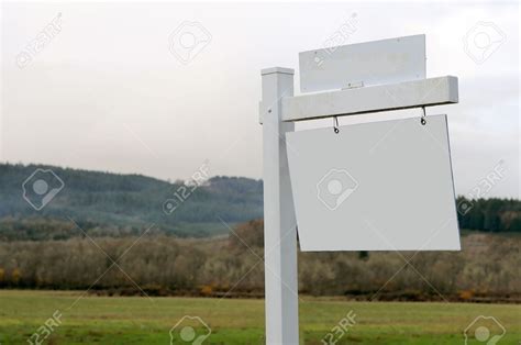8434997 Acres Of Land For Sale With A Blank Wooden Sign Stock Photo