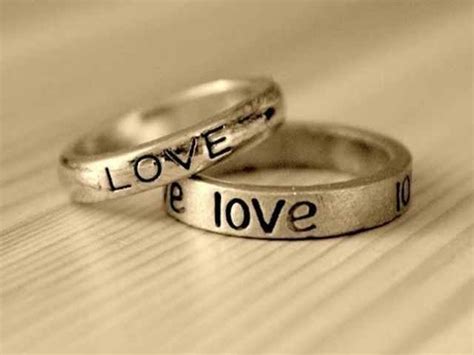 Two Wedding Rings With Words On Them Sitting On Top Of A Wooden Table