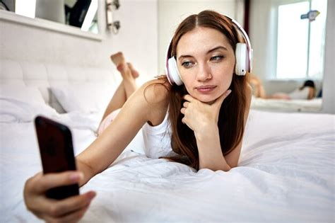 Premium Photo Woman In Headphones Lies In Bed With Smartphone