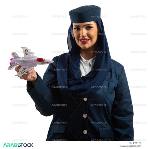 بورتريه لمضيفة طيران عربية خليجية سعودية مبتسمة ترتدي زي مضيفات الطيران تحمل مجسم مصغر لطائرة