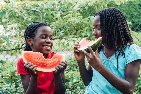 African American Girls Eating Watermelon And Smiling By Stocksy