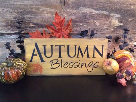 A Wooden Sign That Says Autumn Blessing With Fall Leaves And Acorns