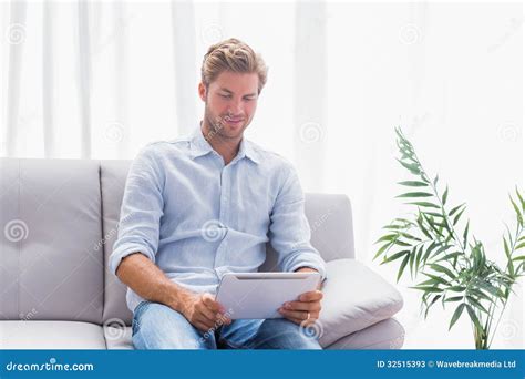 Man Using A Tablet While He Is Sat On The Couch Stock Image Image Of Blonde Attractive