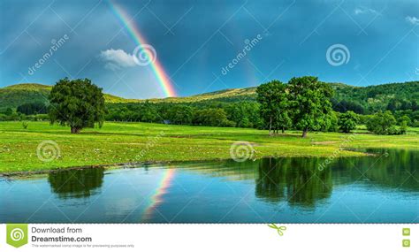 Rainbow Over A Lake Reflected In The Water Stock Image Image Of