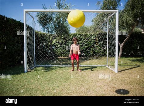 Little Boy Standing In Front Of Soccer Goal Watching Football Stock