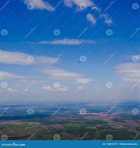 Paragliders Fly Over The Green Plain Under The Blue Sky Stock Image