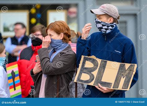 Two Blm Protesters Adjust Their Protective Face Coverings While Holding