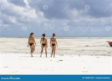Three Girls In Swimsuits Go To The Ocean On The Tropical Sand Beach Of Zanzibar Island Tanzania
