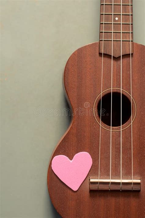 An Ukulele With A Handmade Heart Placing On The Isolated Blue Wooden