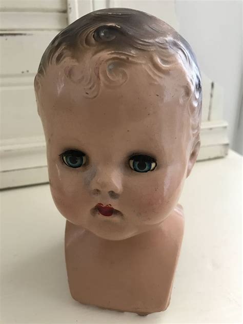 An Old Doll Head Sitting On Top Of A White Table Next To A Door With