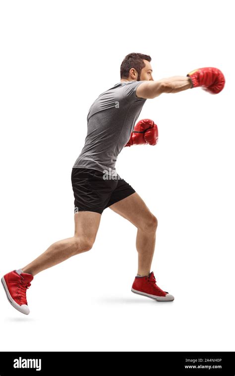 Full Length Profile Shot Of A Young Guy Punching With Boxing Gloves Isolated On White Background