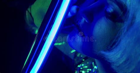 close up of a woman with makeup and white hair looking at the blue neon light 4k stock footage