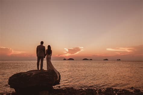 Couple on rock looking out at sunset sea - photo by Ed Peers Photography