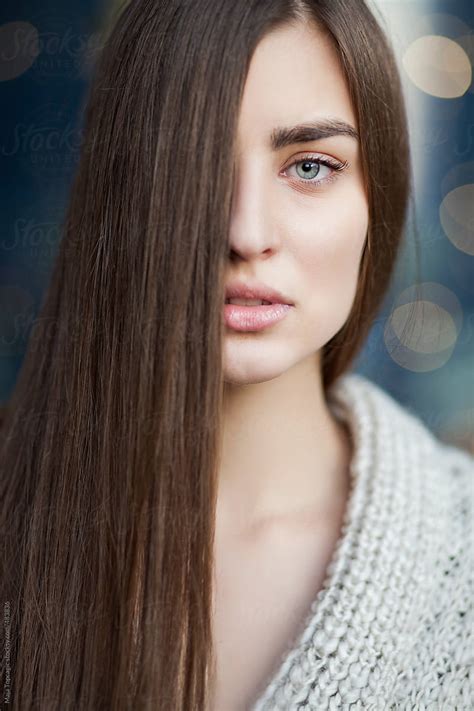 Young Beautiful Woman With Blue Eyes And Long Brown Hair Covering Half