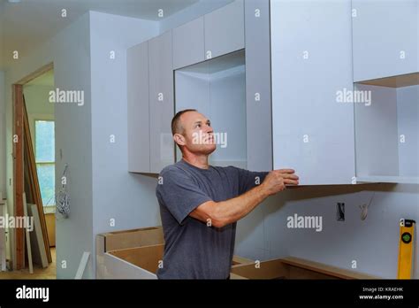 Closeup Of A Cabinet Installer Installing Hardware On New Kitchen