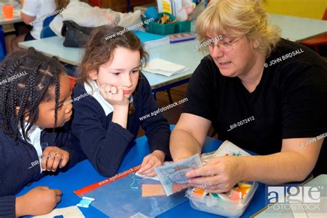 Teacher Showing Primary School Pupils How To Sew During A Needlework