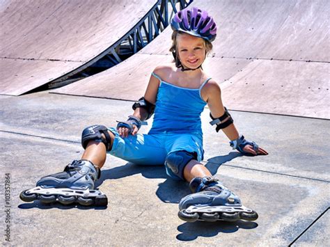 Girl Wearing Roller Skates And Helmet Sitting On Ride In Skatepark
