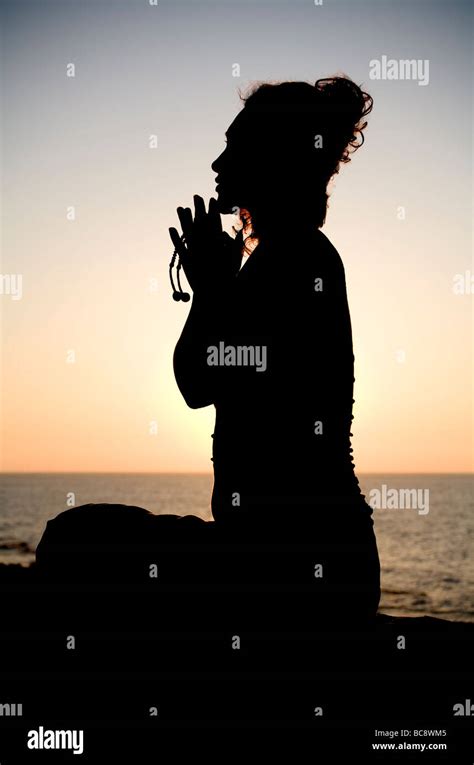 Silhouette Of Young Woman Praying At Sunset Seaside Stock Photo Alamy