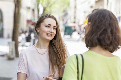 Beautiful Woman Talking With Friend On Footpath Stock Photo