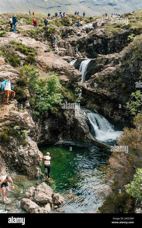 Tourists Swim And Clamber Over Waterfalls And Rocks At The Fairy Pools