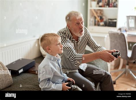 Grandfather And Grandson Playing Video Games On Computer With Joystick
