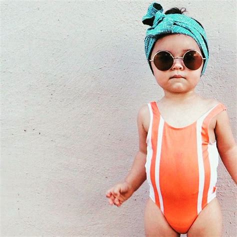 Un Naranjo Y Blanco Striped One Piece Por Un Round Sunglasses Y Azul