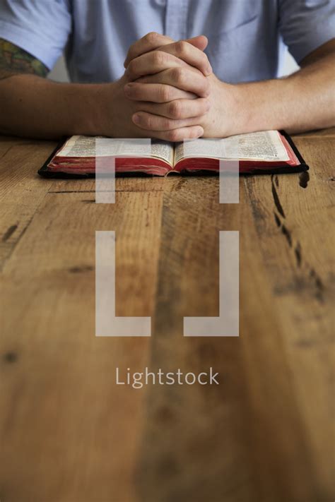 Man With Praying Hands Over A Bible — Photo — Lightstock